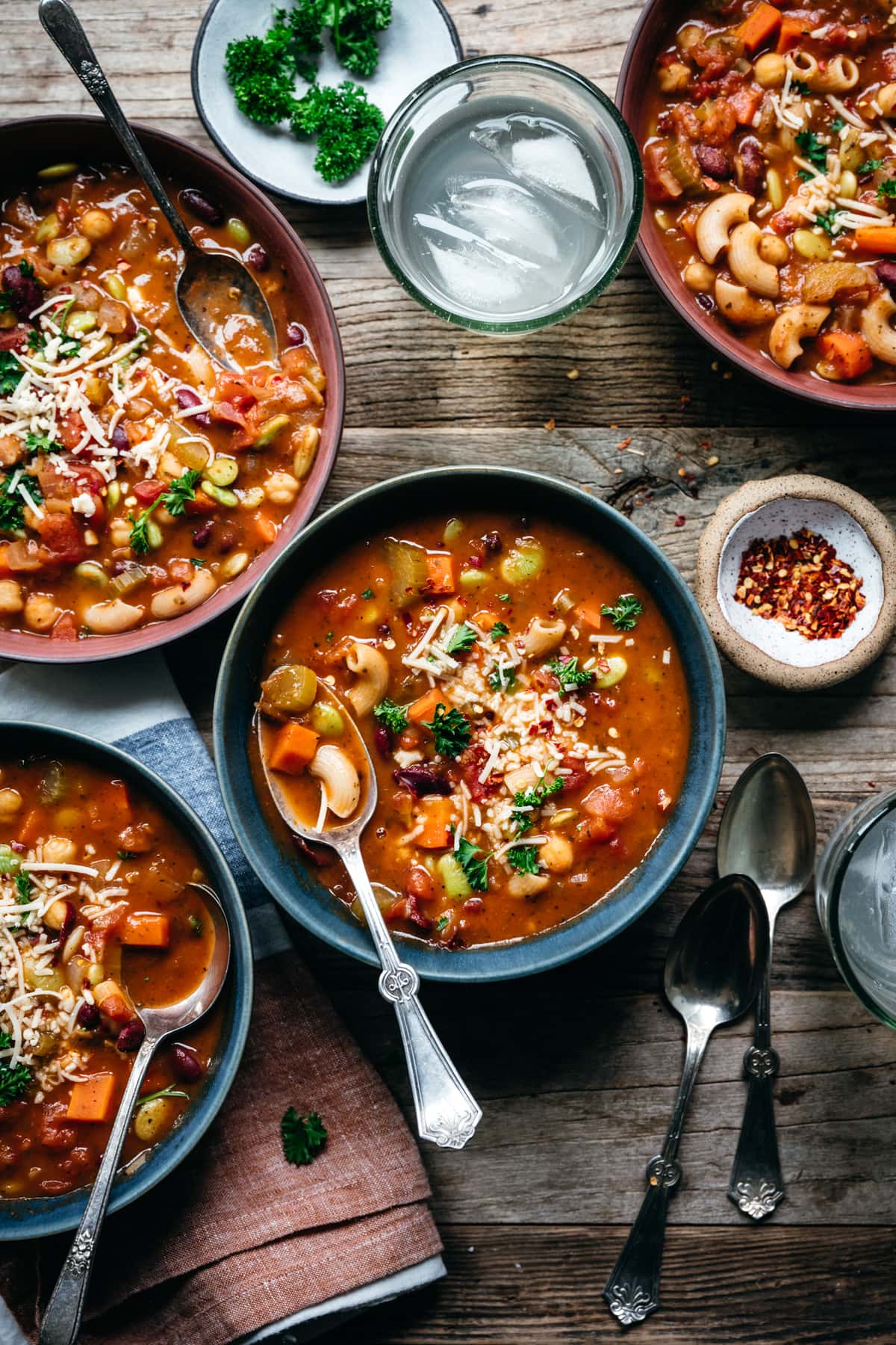 overhead view of vegan minestrone soup in blue bowls on wood table