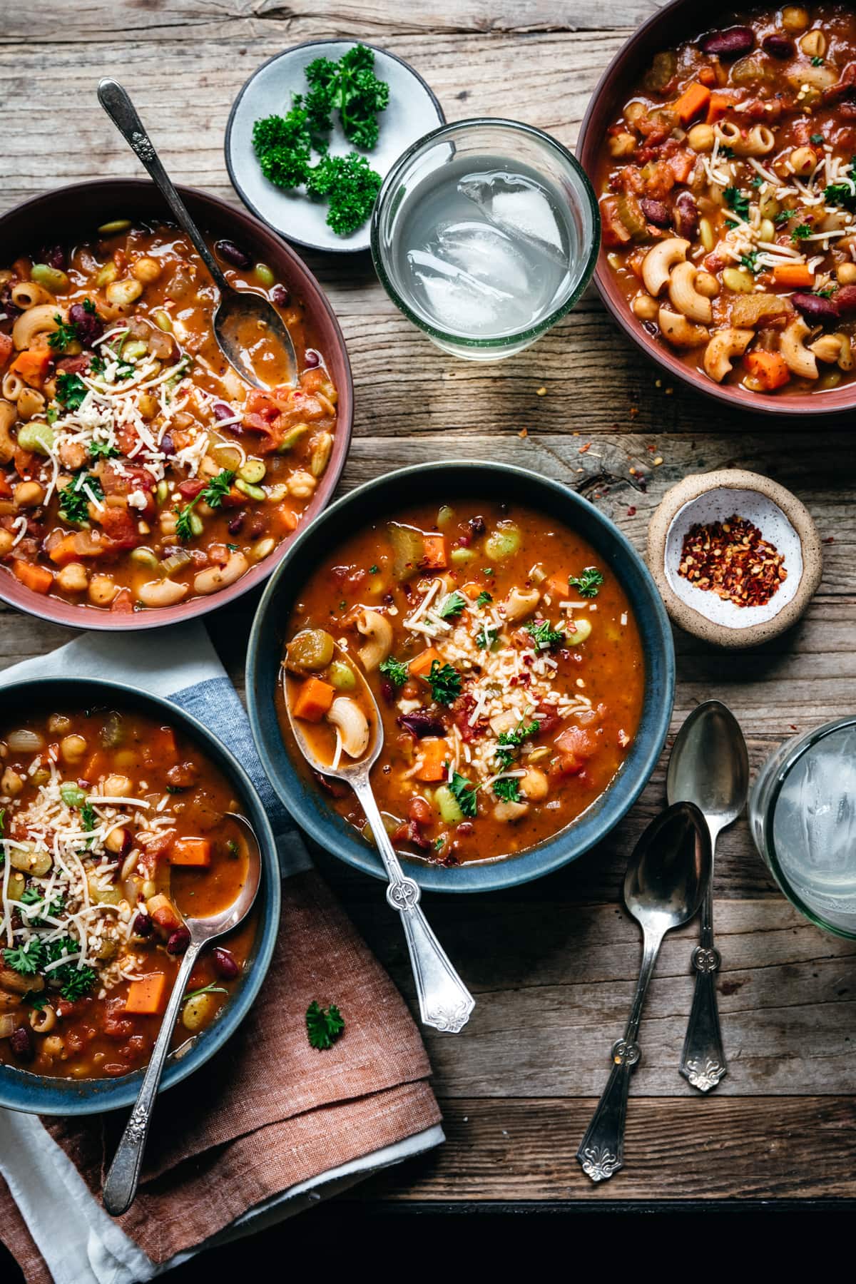 overhead view of healthy vegetable minestrone soup in blue bowls on wood table