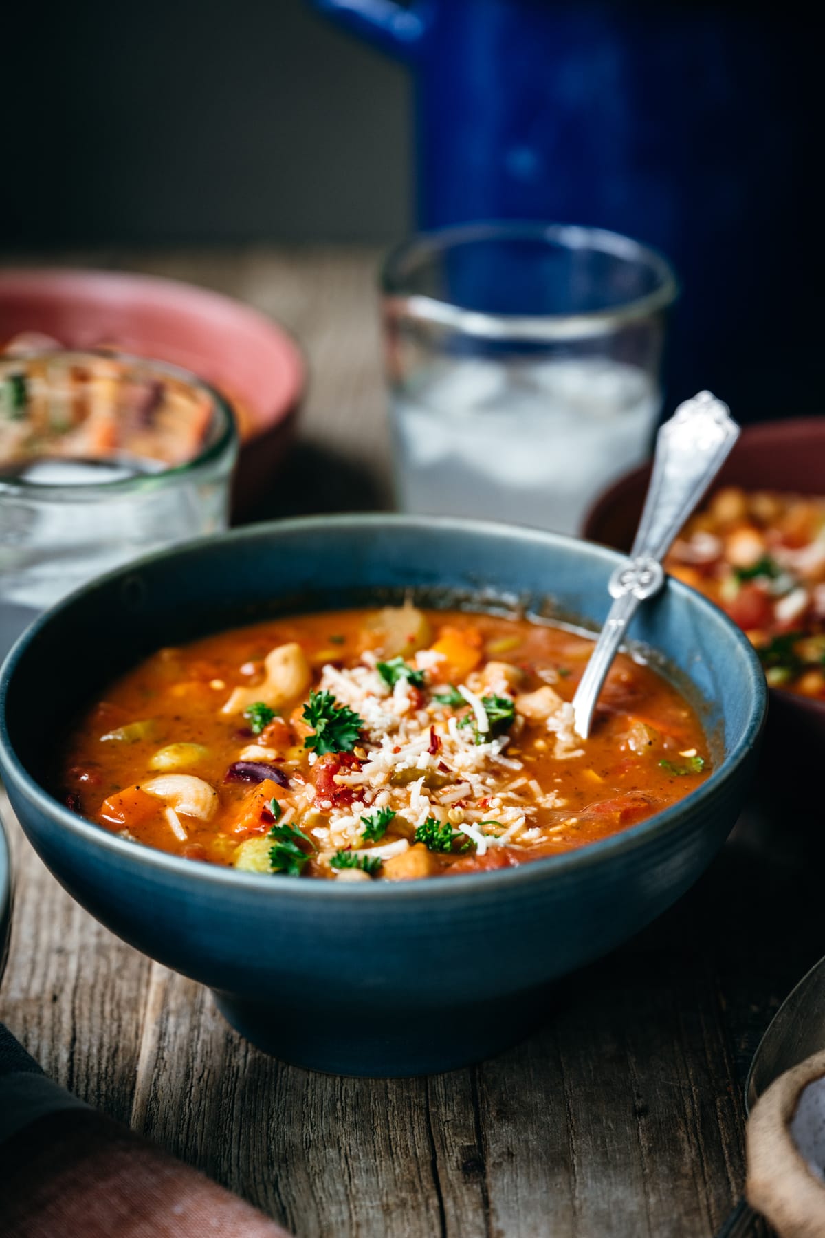 side view of vegetable minestrone with vegan ingredients in blue bowl