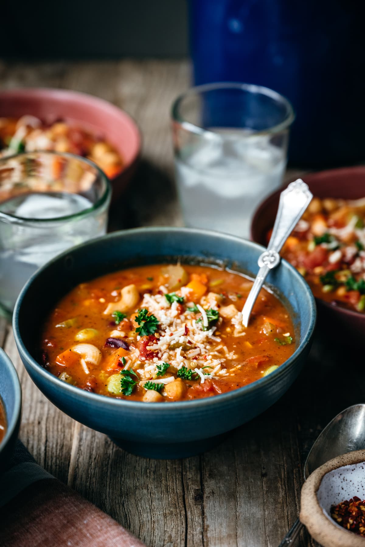 side view of vegetable minestrone with vegan ingredients in blue bowl