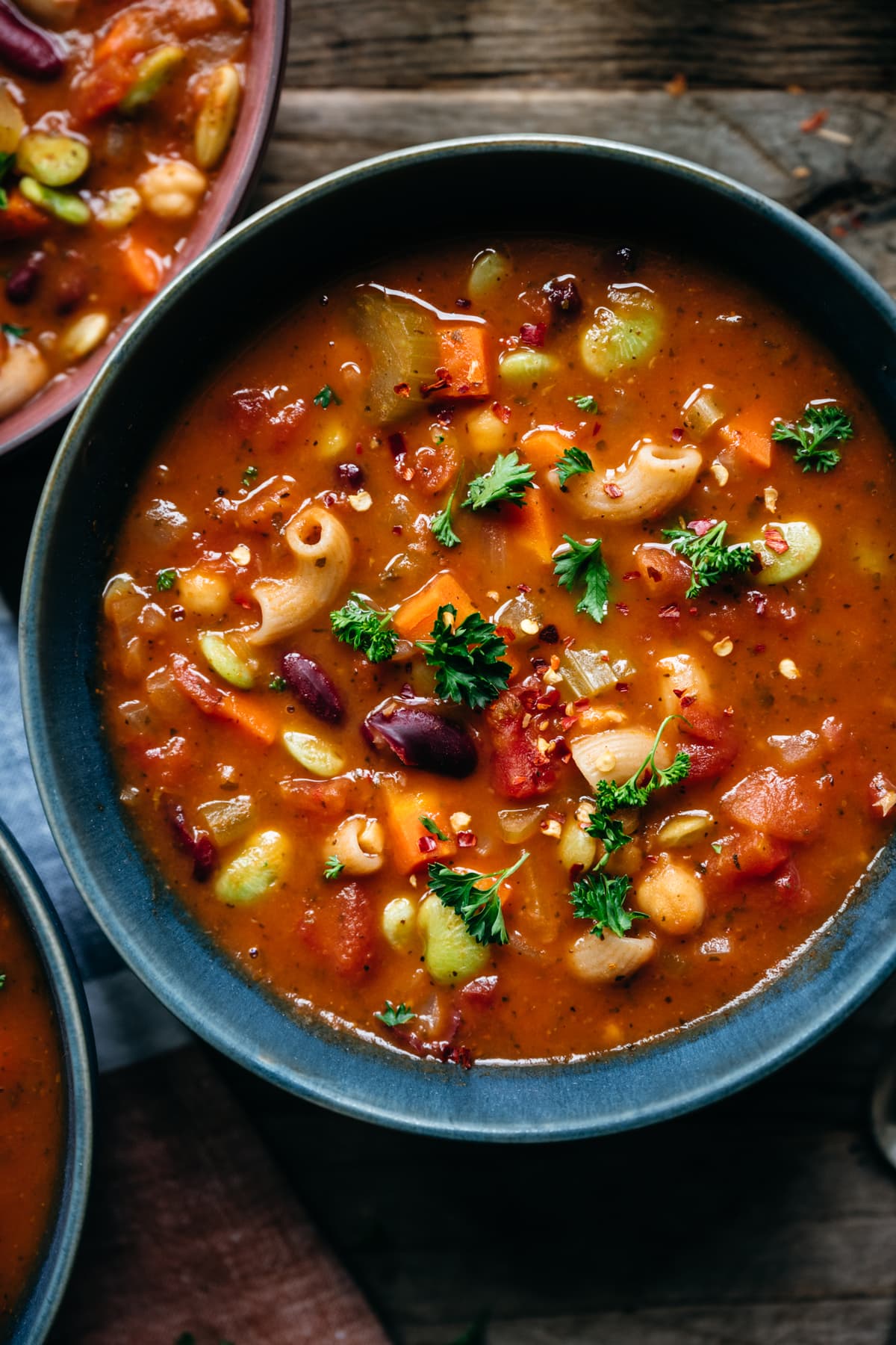 close up view of vegan minestrone soup in blue bowl