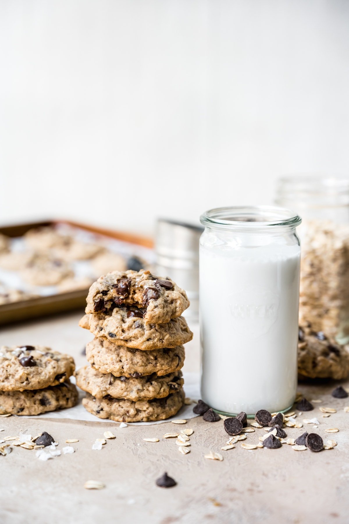 side view of stack of oatmeal raisin chocolate chip cookies next to a glass of milk