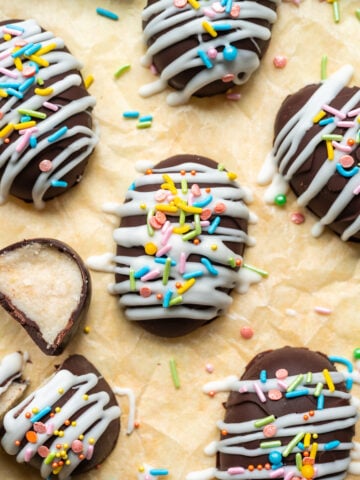 Chocolate coconut easter eggs with white chocolate and sprinkles on yellow backdrop.