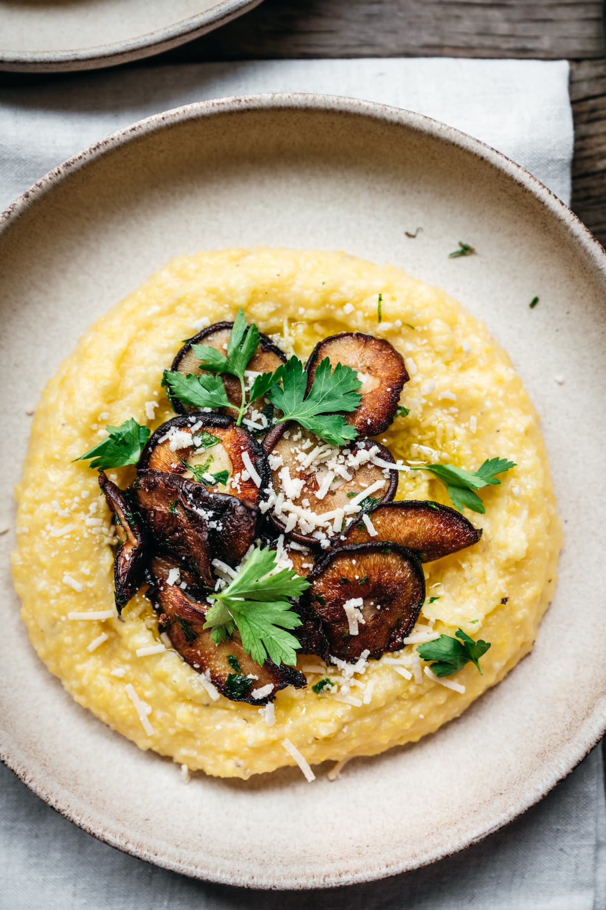 close up overhead view of vegan polenta with pan seared mushrooms and herbs