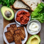 Tofu bacon from above with avocados and bread on a platter.