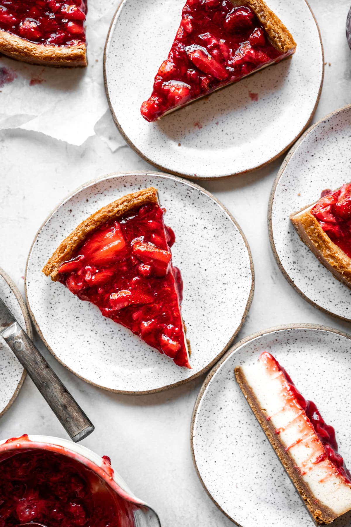 overhead view of slices of baked strawberry vegan cheesecake on small plates