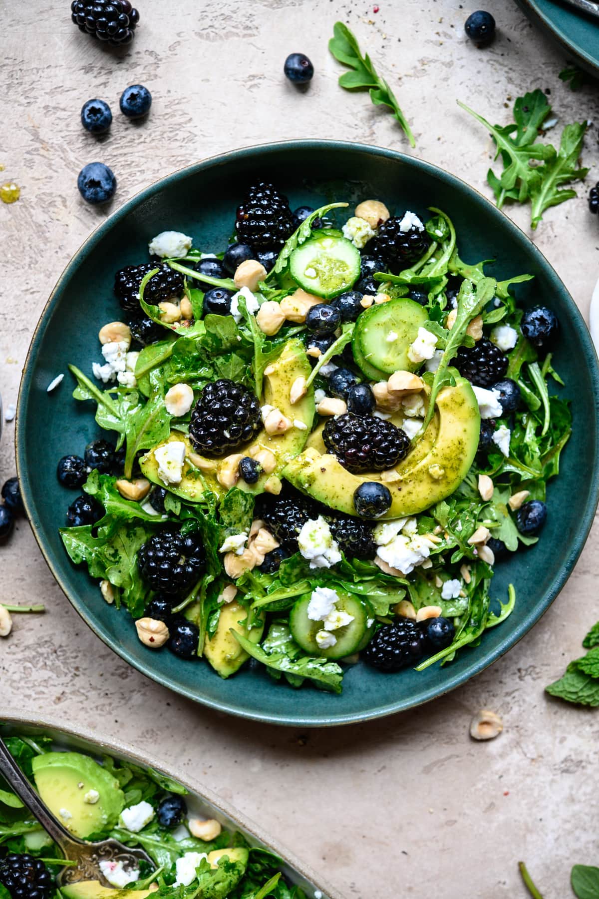 overhead view of blackberry avocado arugula salad in blue bowl