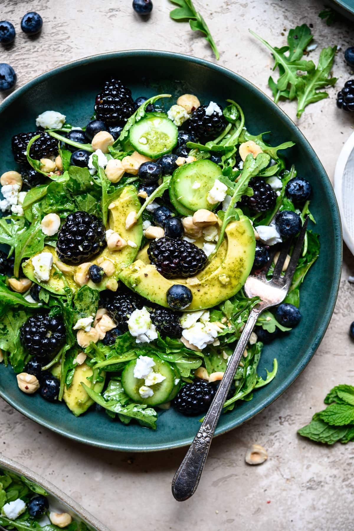 overhead view of blackberry avocado arugula salad in blue bowl