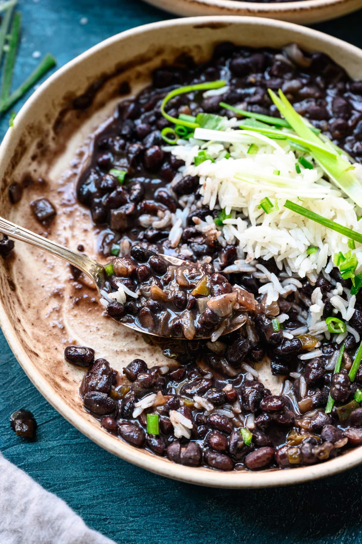 close up view of cuban-style black beans on spoon in bowl