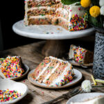 Funfetti cake on a cake stand with slices of cake on plates below.