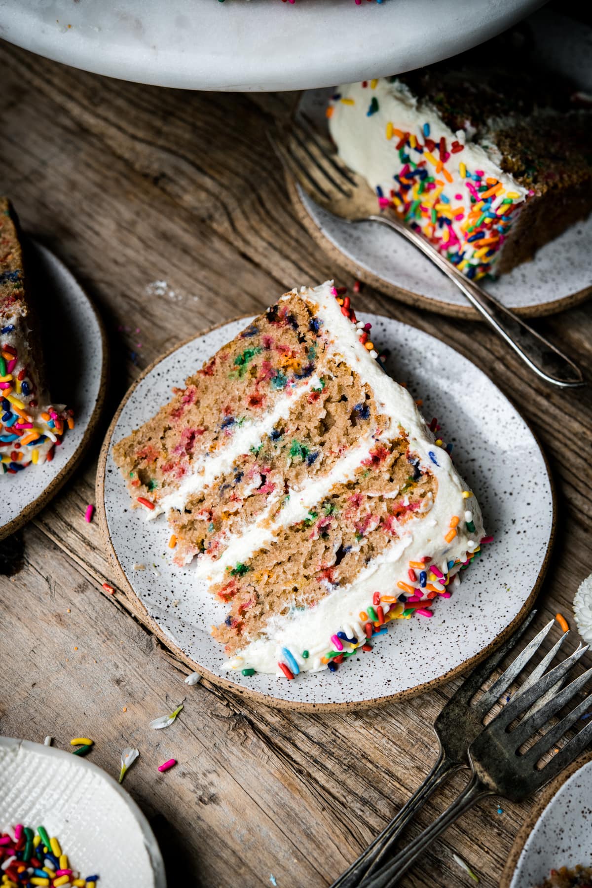 side view of a slice of vegan gluten free funfetti vanilla cake on a small plate