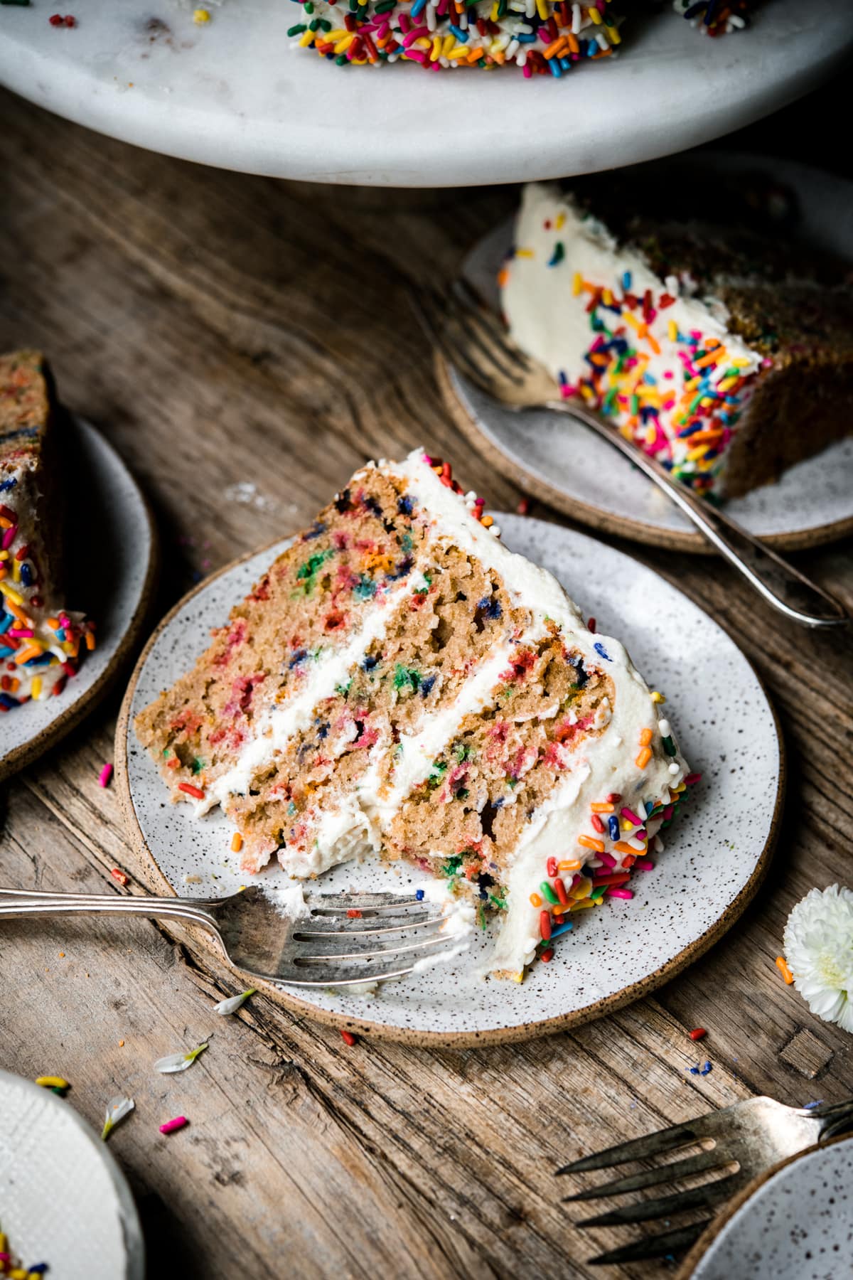 side view of a slice of vegan gluten free funfetti vanilla cake on a small plate