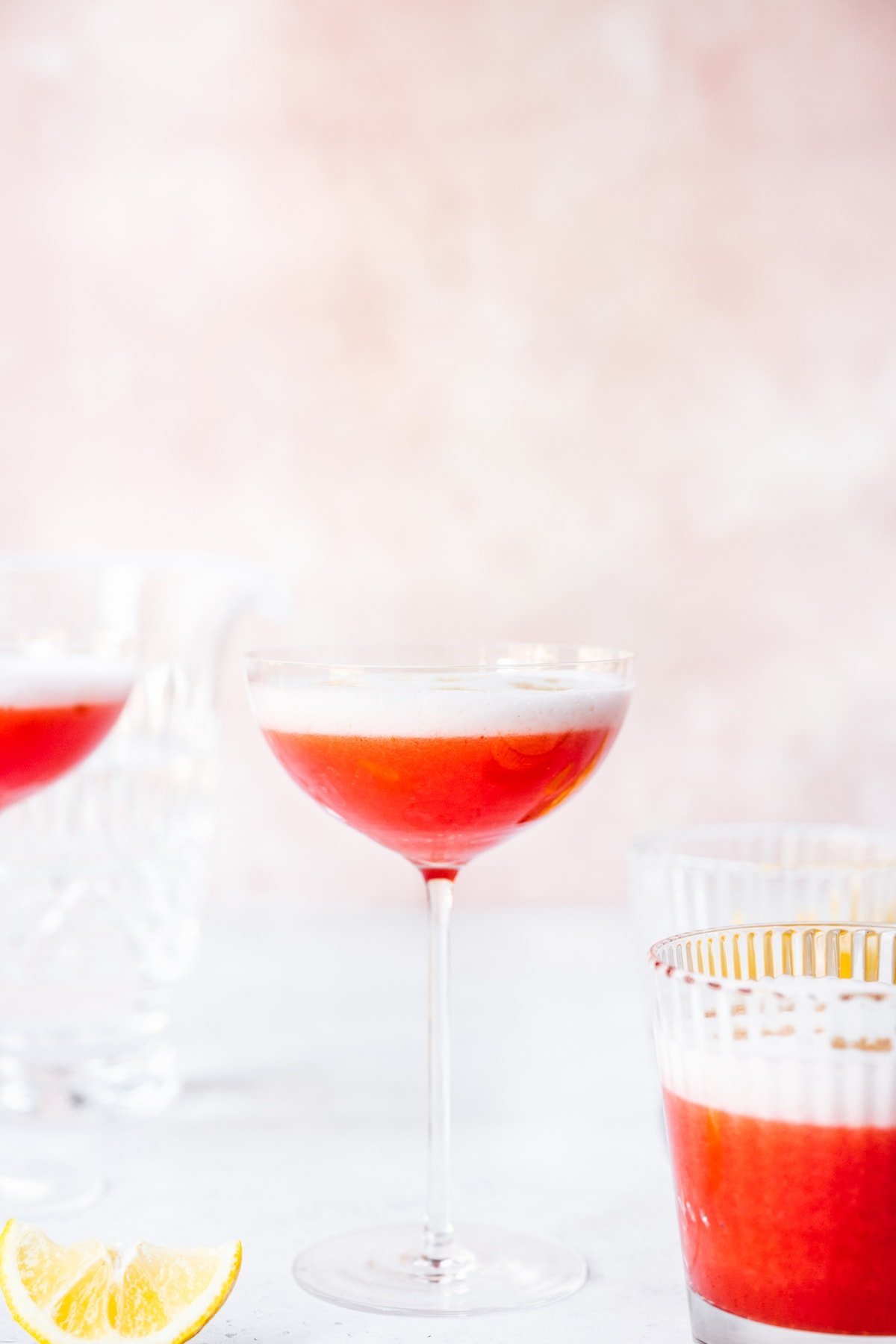 side view of vegan strawberry pisco sour in a coupe glass