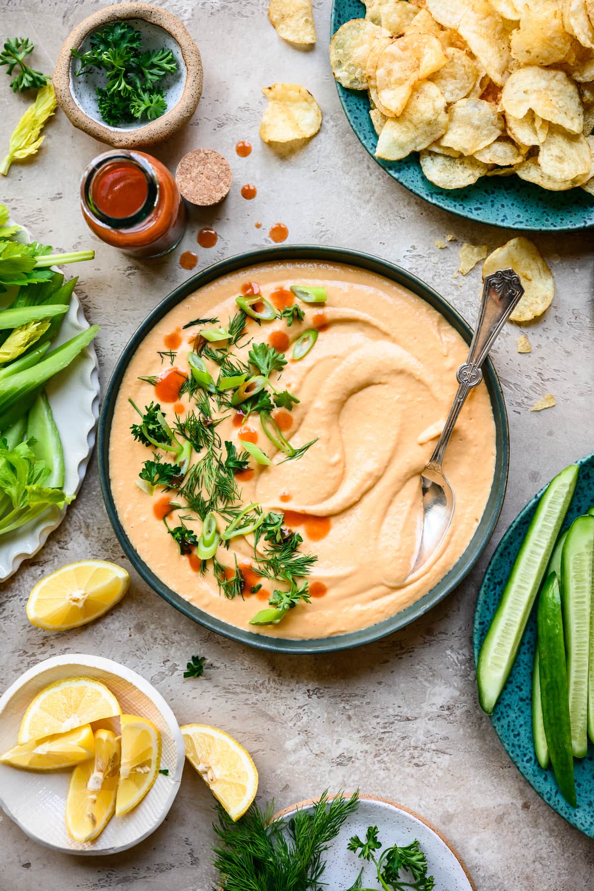 overhead view of vegan buffalo dip in a bowl with vegetables and chips
