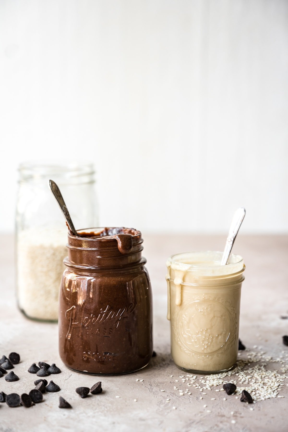 side view of homemade tahini and chocolate tahini in glass jars