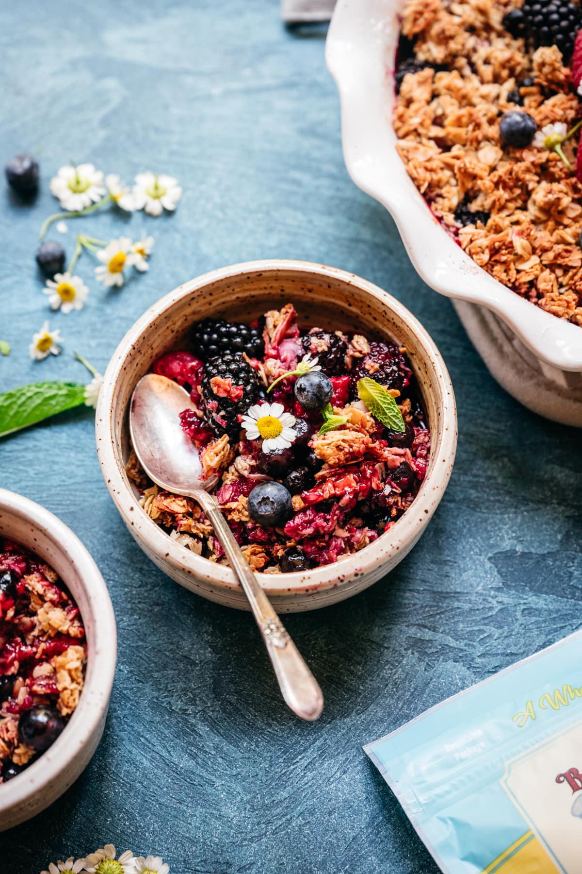 triple berry granola crisp in a small bowl with spoon