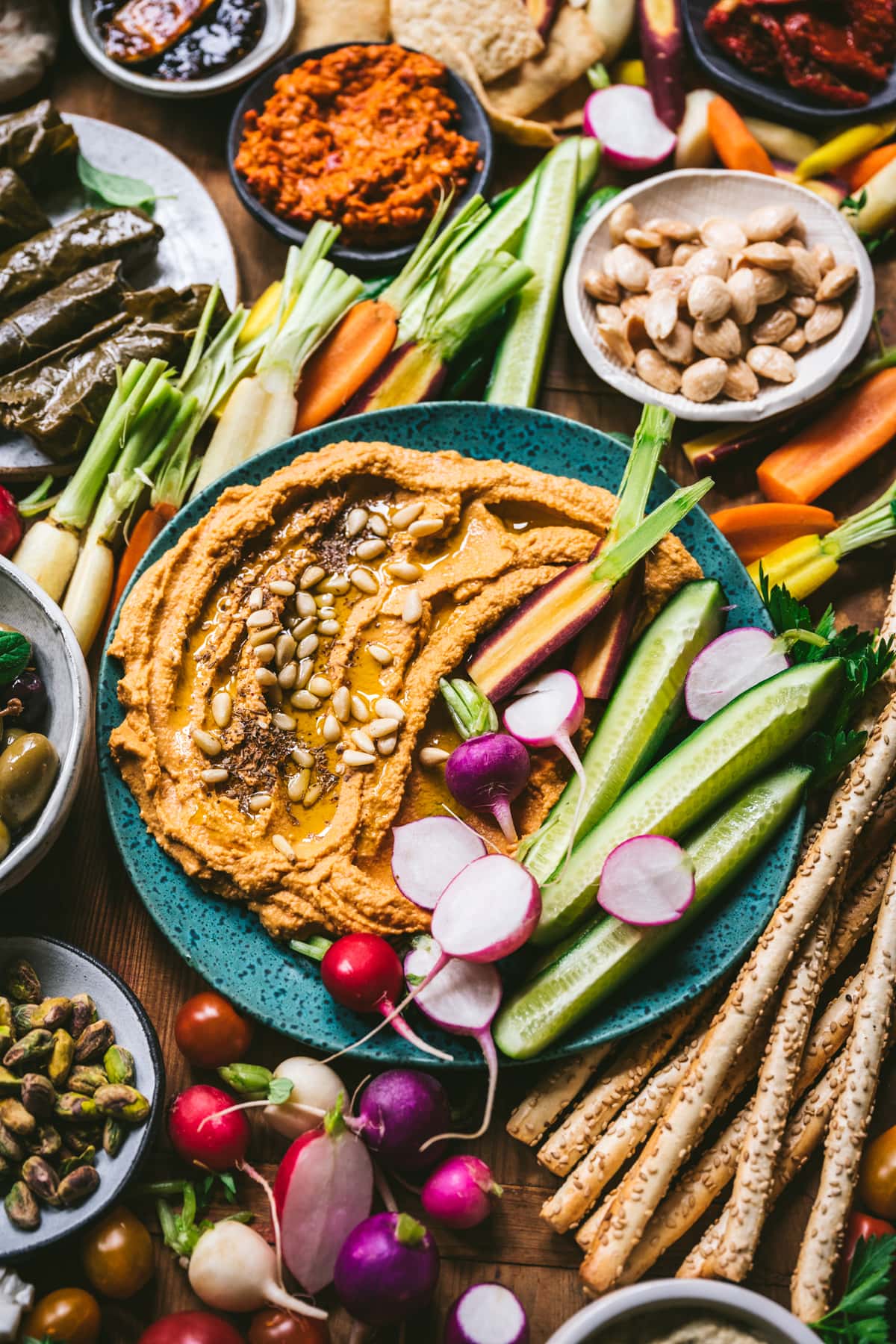 close up view of roasted red pepper hummus with fresh vegetables for dipping