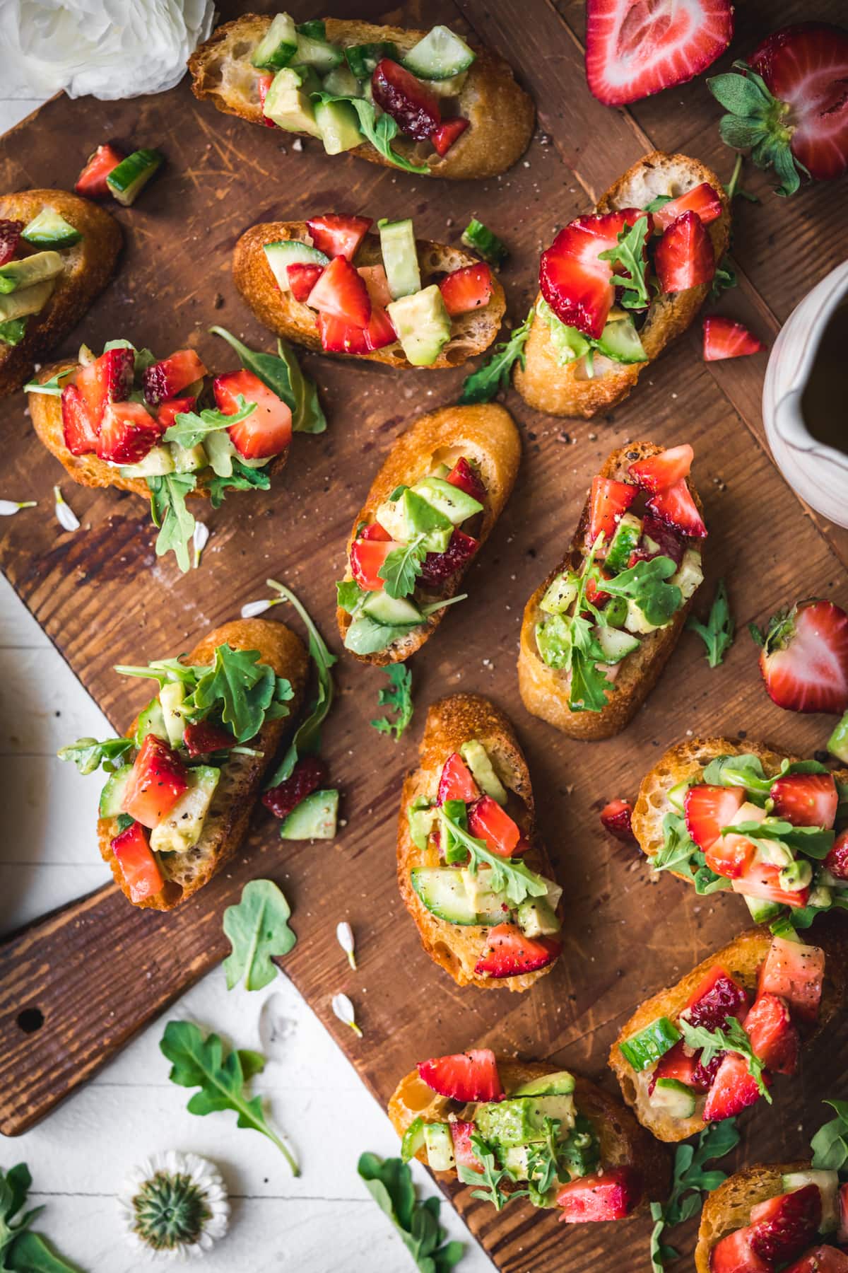 overhead view of summer crostini with strawberries avocado and cucumber