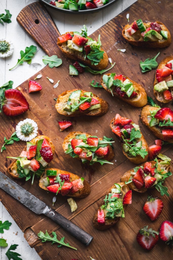 overhead view of summer crostini with strawberries avocado and cucumber