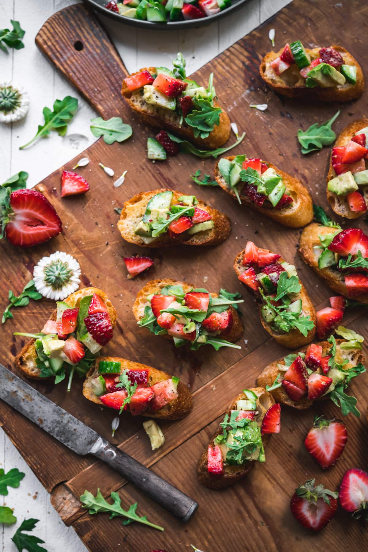 overhead view of summer crostini with strawberries avocado and cucumber