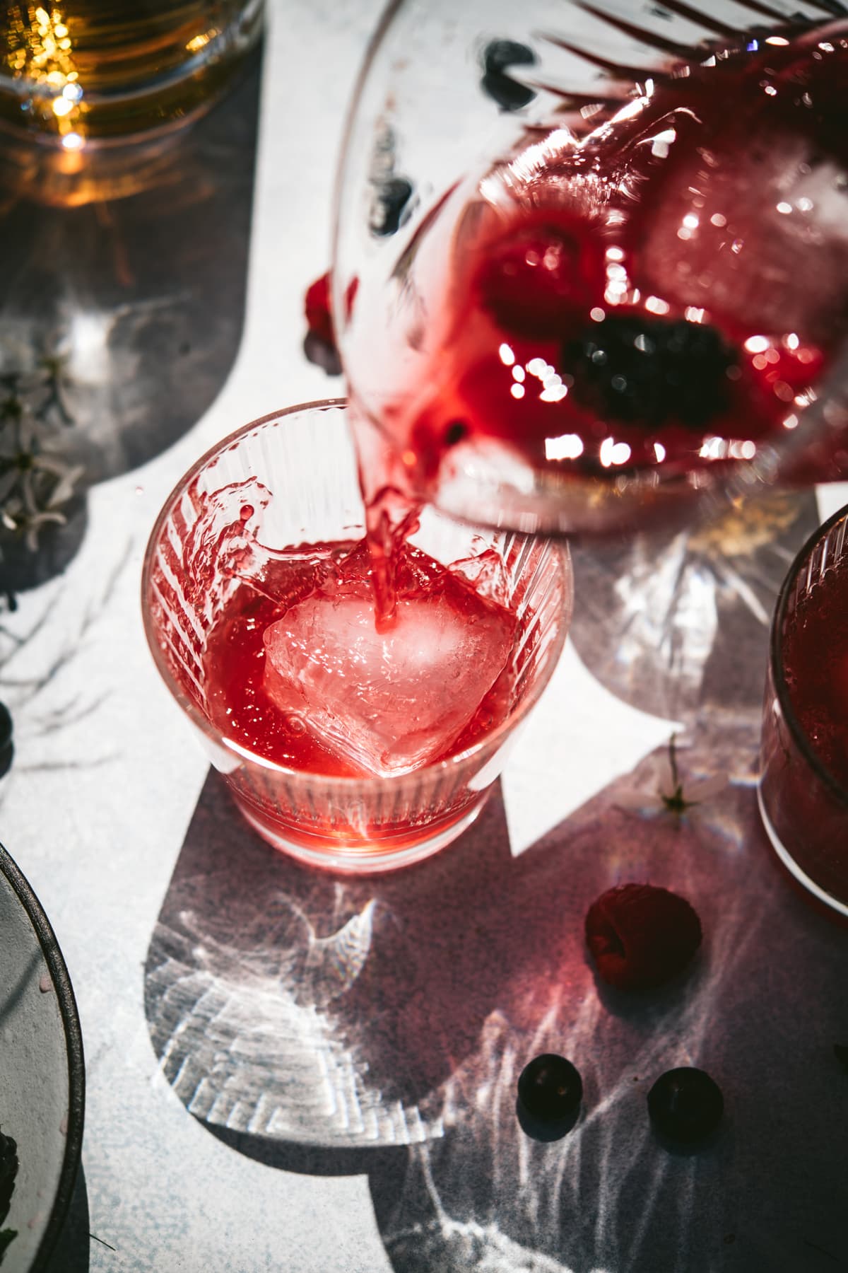 pouring berry bourbon pitcher cocktail into glass