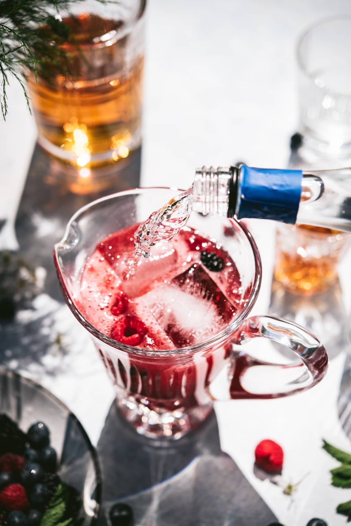 pouring club soda into summer pitcher cocktail