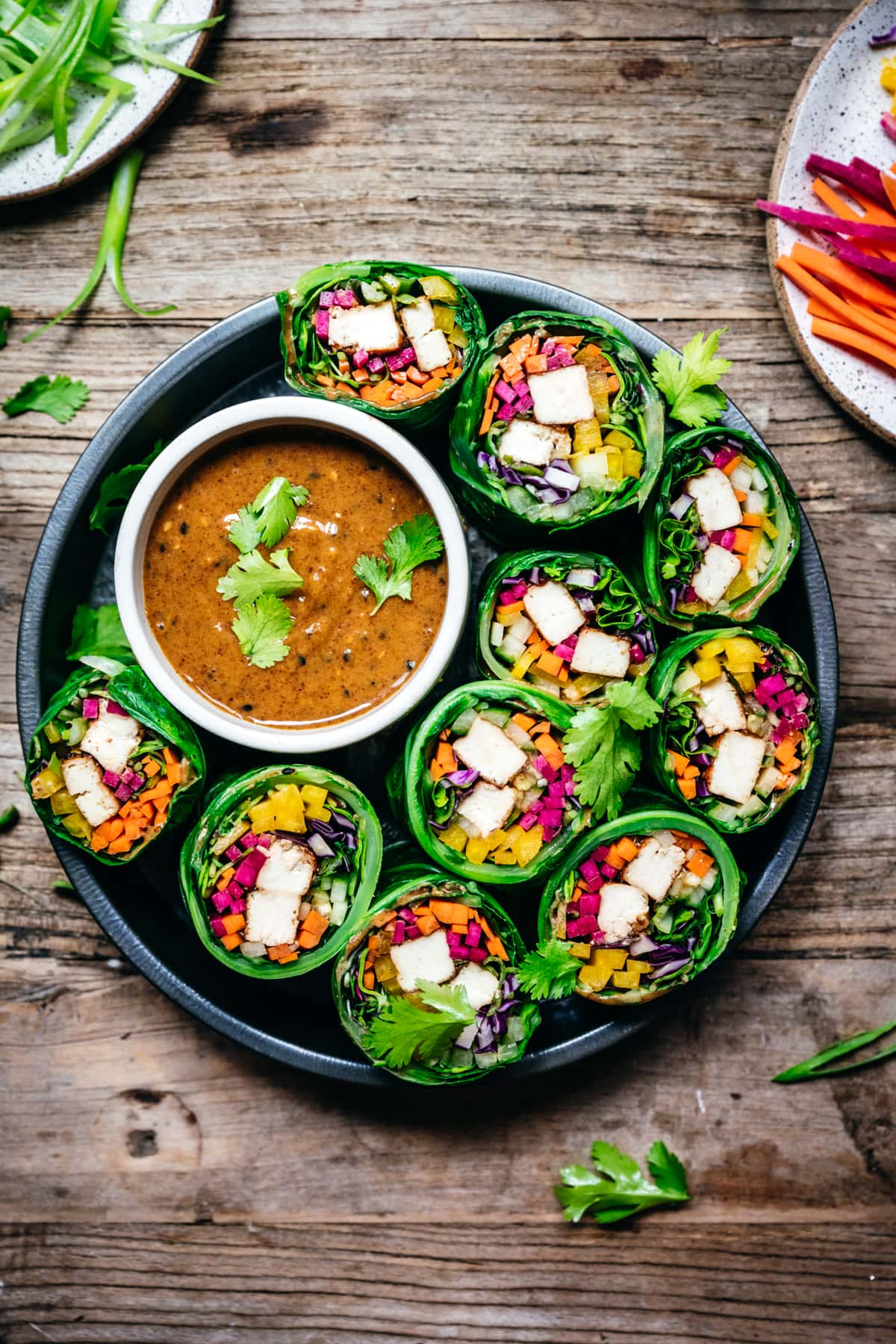 overhead view of vegan collard green wraps with vegetables and tofu cut in half with almond miso sauce