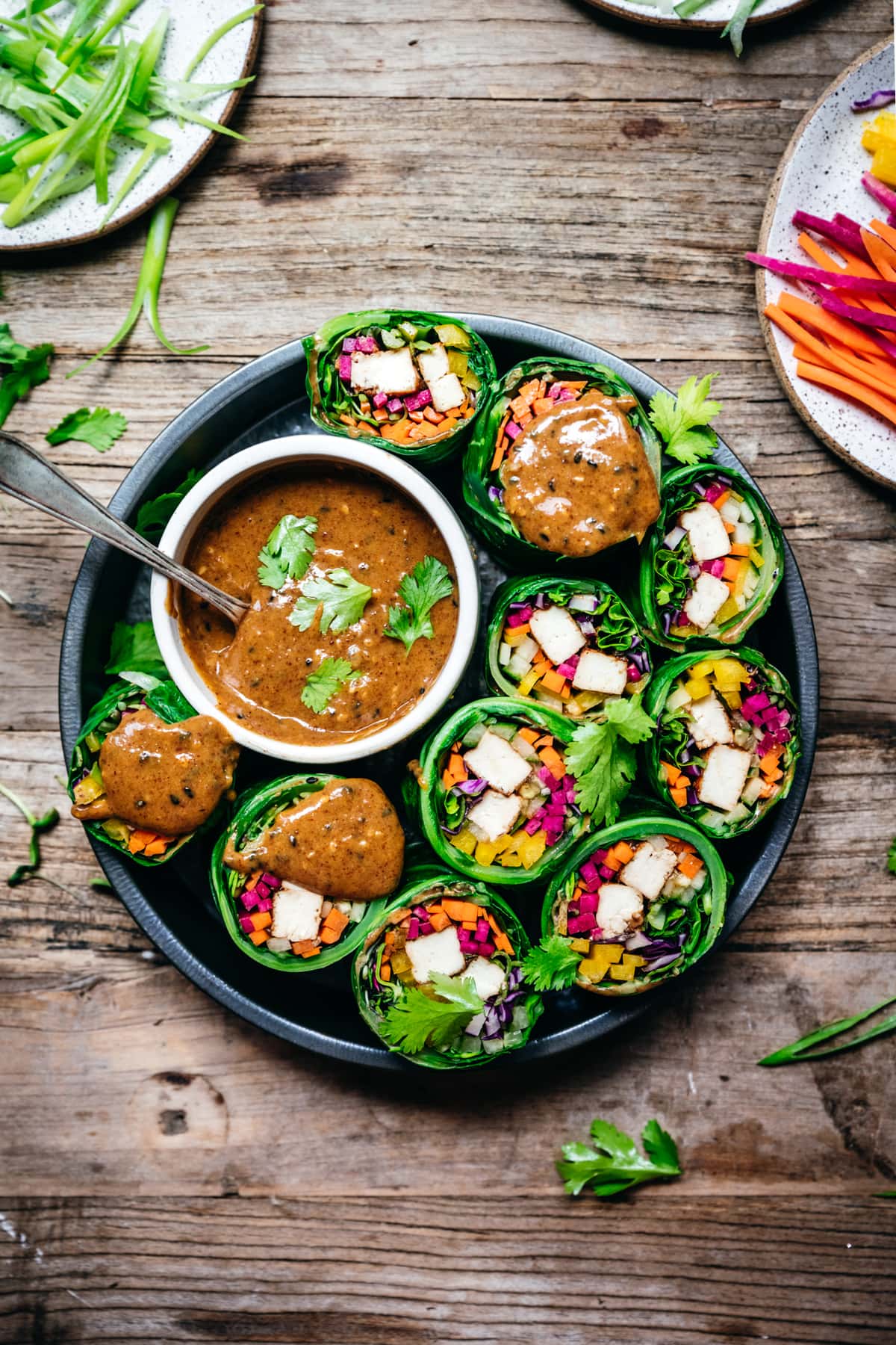 overhead view of vegan collard green wraps with vegetables and tofu cut in half with almond miso sauce