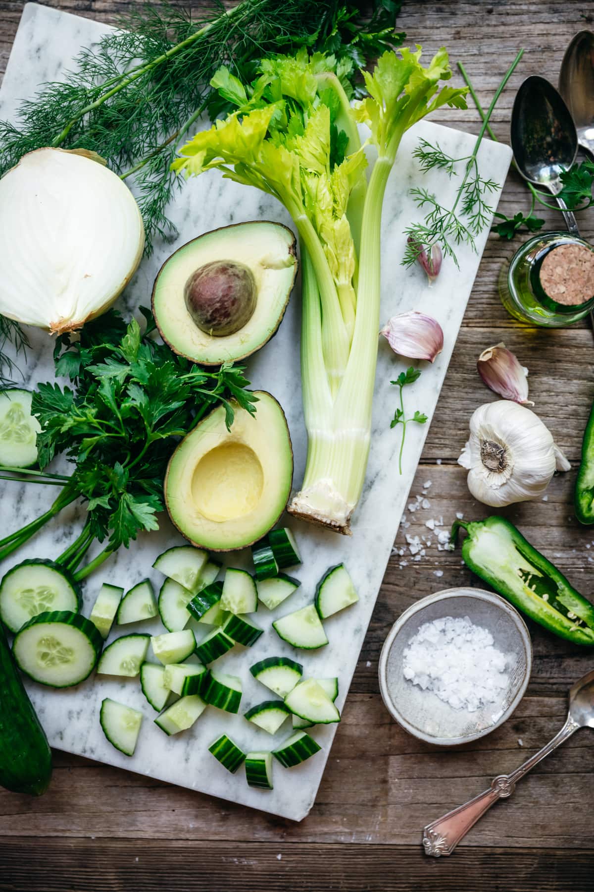 overhead view of ingredients for vegan cucumber avocado gazpacho on marble cutting board