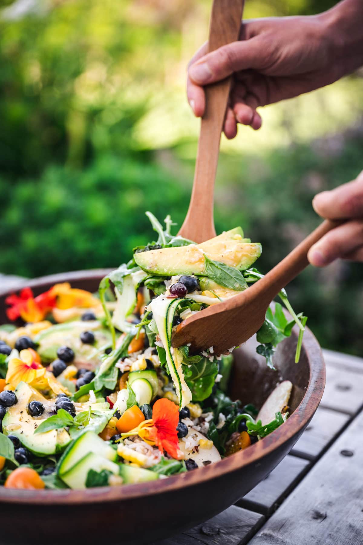 person using tongs to serve summer vegetable salad