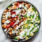 overhead view of vegan avocado BLT salad with ranch dressing on marble backdrop