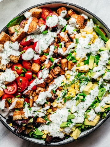 overhead view of vegan avocado BLT salad with ranch dressing on marble backdrop