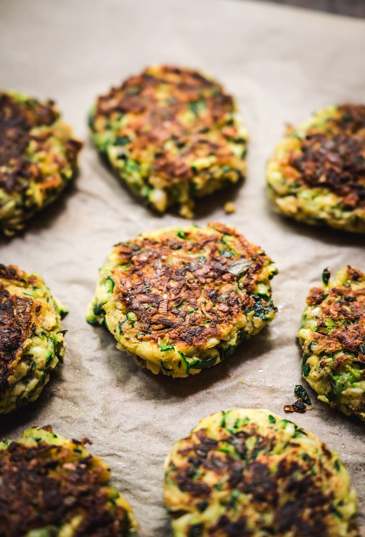 side view of vegan zucchini fritters on parchment paper