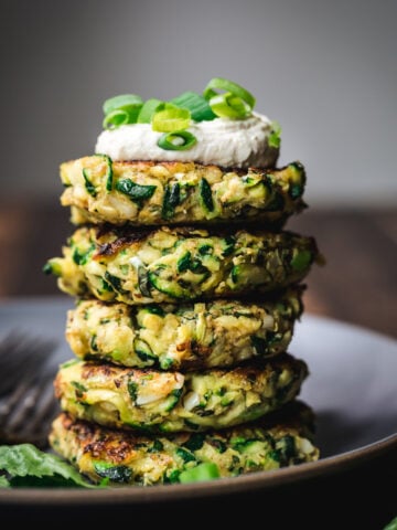 side view of stack of vegan zucchini fritters on a plate