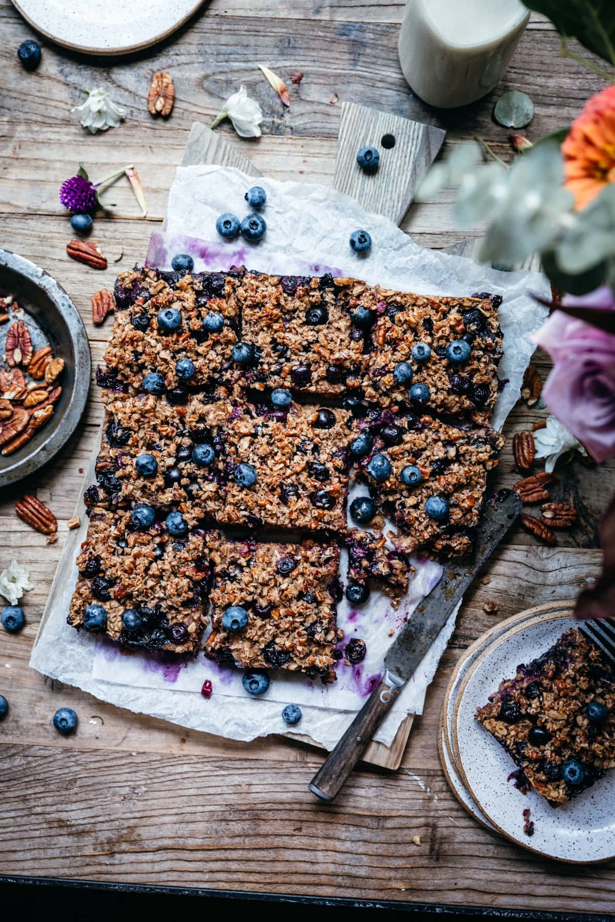 overhead view of vegan blueberry pecan baked oatmeal sliced into squares on wood cutting board