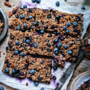 overhead view of vegan blueberry pecan baked oatmeal sliced into squares on wood cutting board