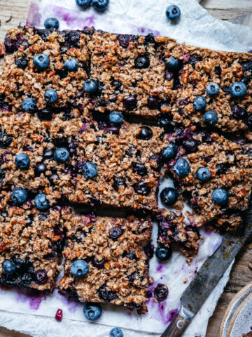 overhead view of vegan blueberry pecan baked oatmeal sliced into squares on wood cutting board