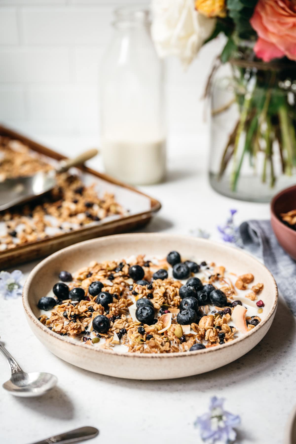 side view of blueberry lemon granola in a bowl with milk and blueberries