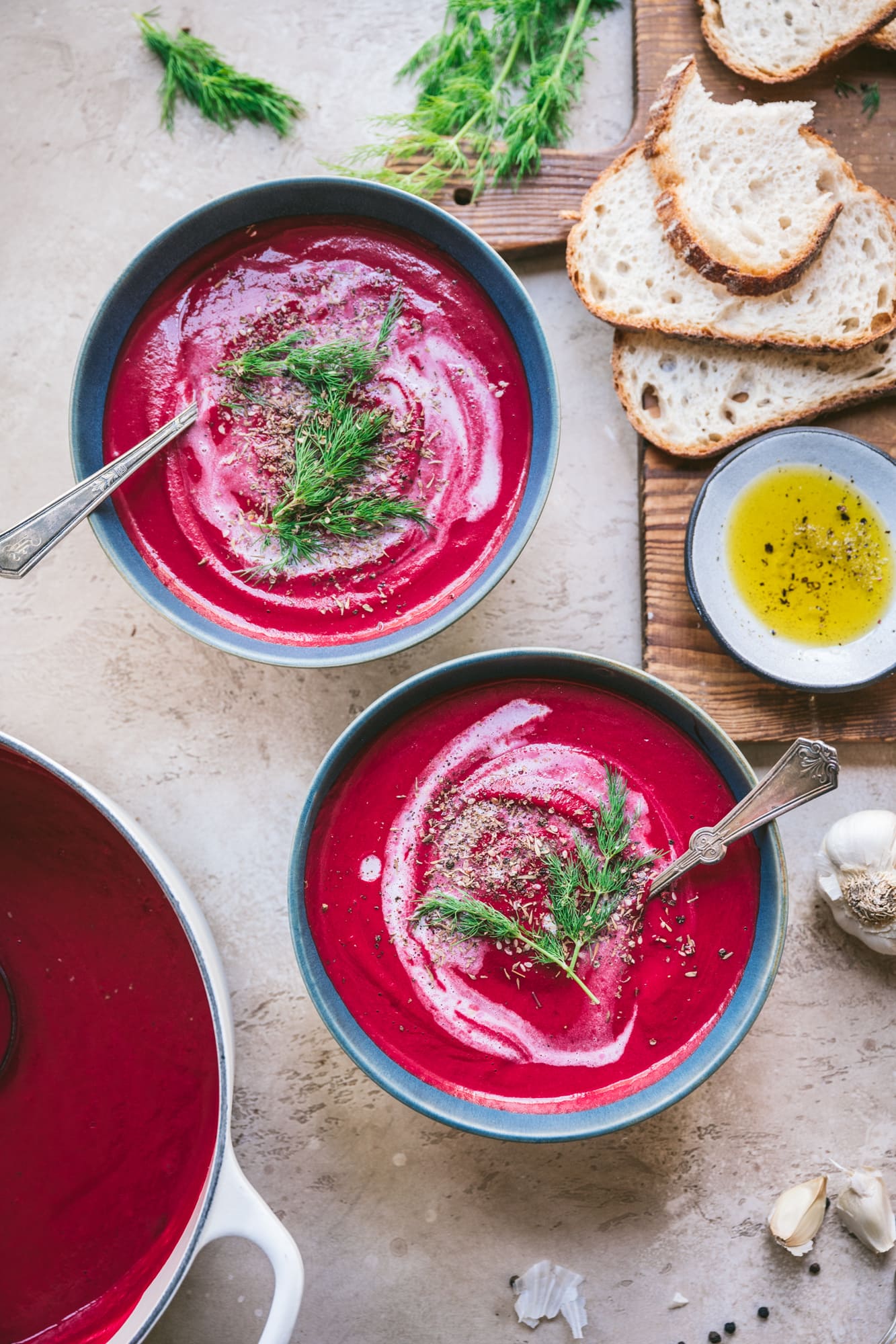 overhead view of two bowls of creamy vegan roasted beet soup in blue bowls