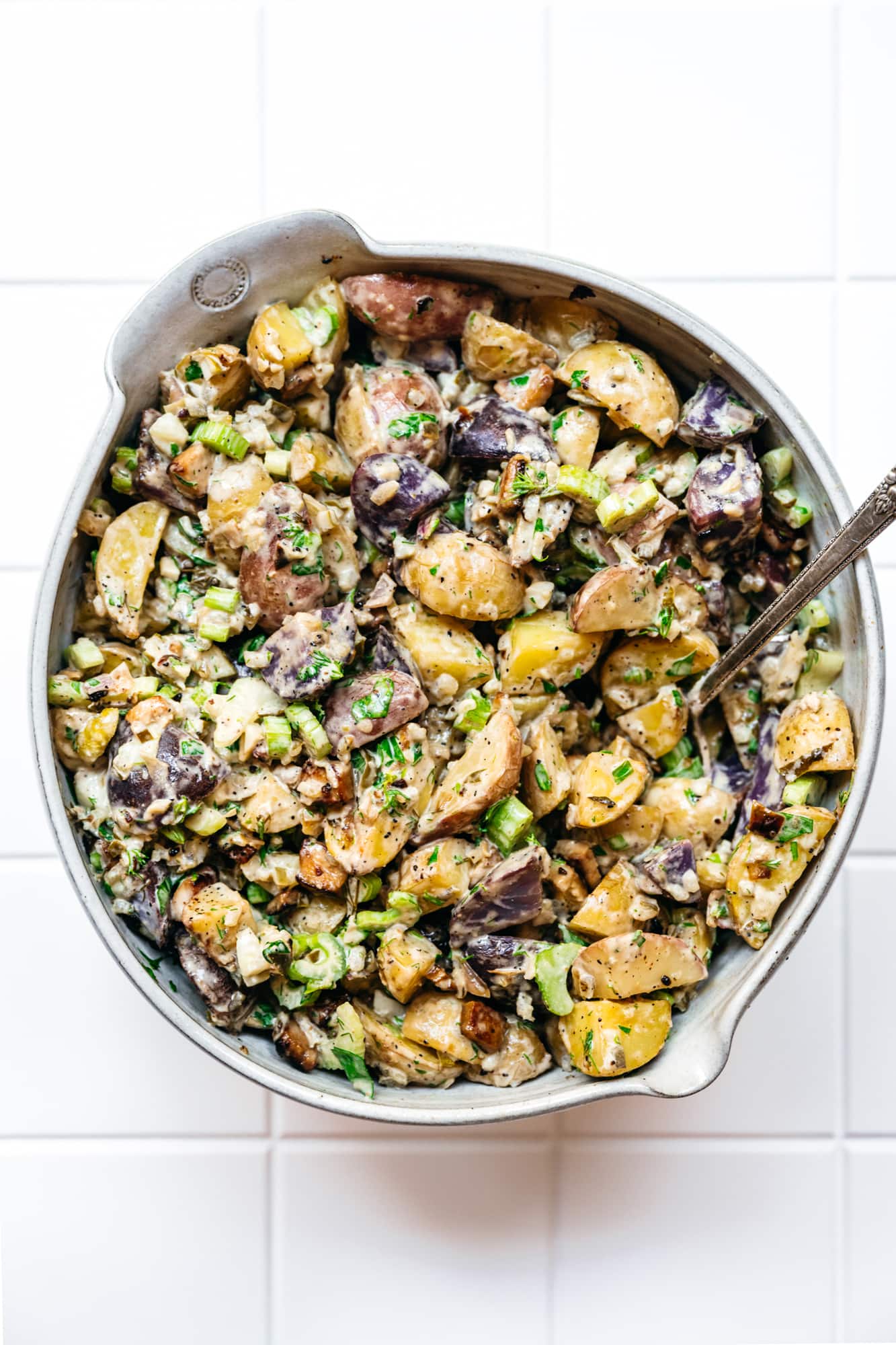 overhead view of vegan dill pickle potato salad in large white bowl