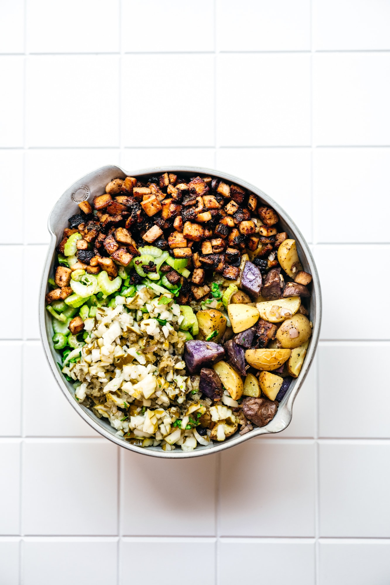 overhead view of ingredients in bowl for dill pickle potato salad