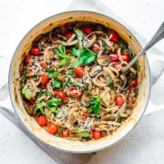 overhead view of vegan one pot pasta in a dutch oven with mushrooms and tomatoes.