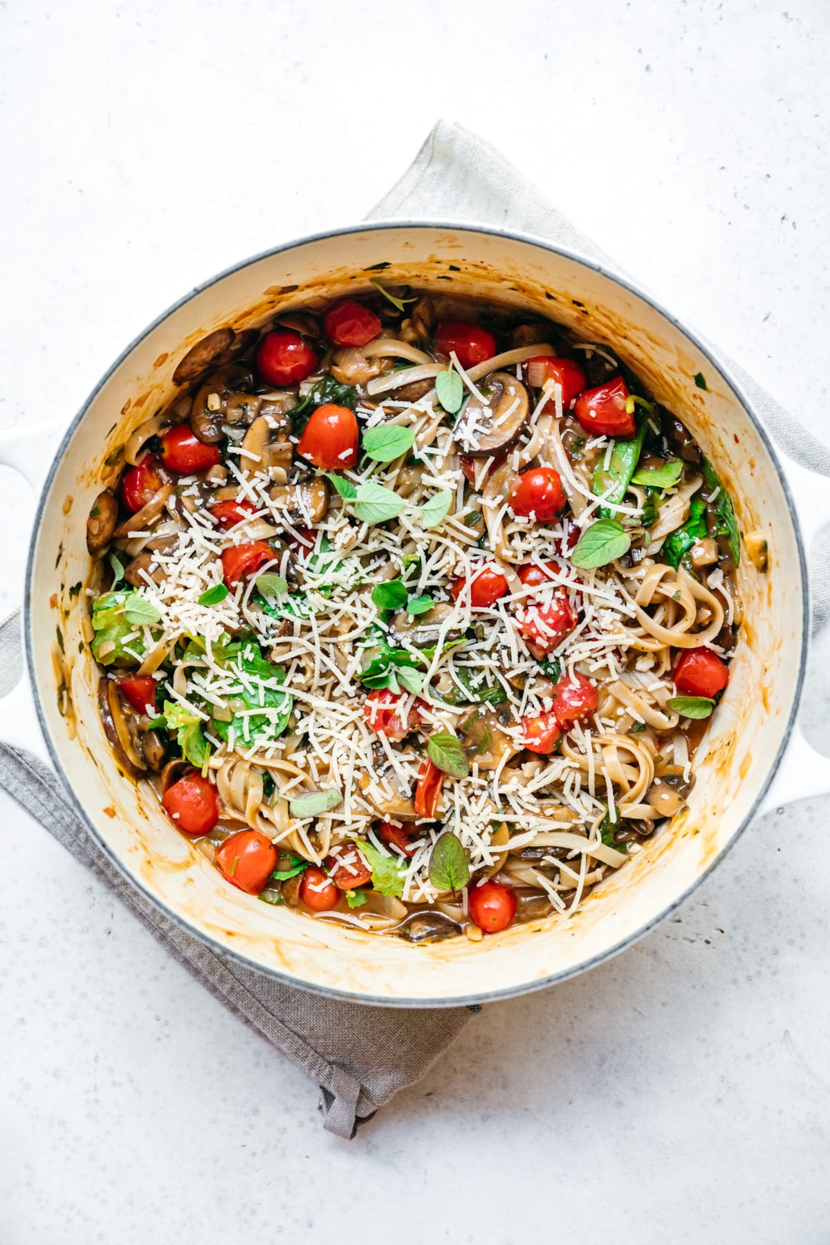 overhead view of vegan one pot pasta in a dutch oven with mushrooms and tomatoes.