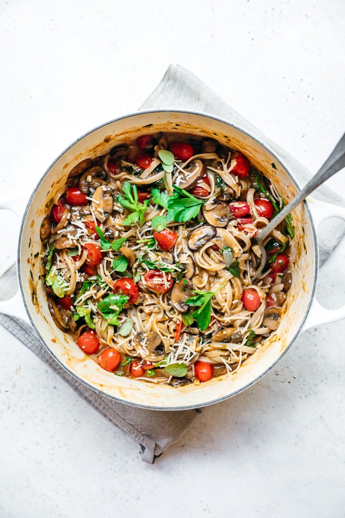 overhead view of vegan one pot pasta in a dutch oven with mushrooms and tomatoes.