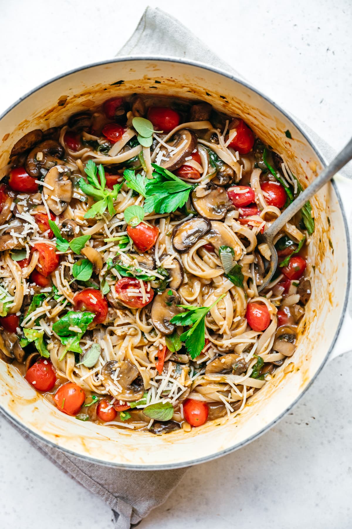 overhead view of vegan one pot pasta in a dutch oven with mushrooms and tomatoes.