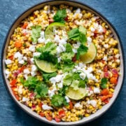 overhead view of bowl of vegan mexican street corn salad with limes and cilantro