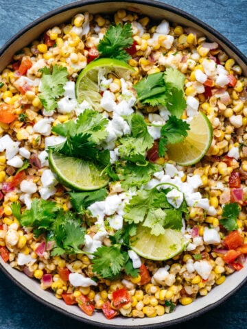 overhead view of bowl of vegan mexican street corn salad with limes and cilantro