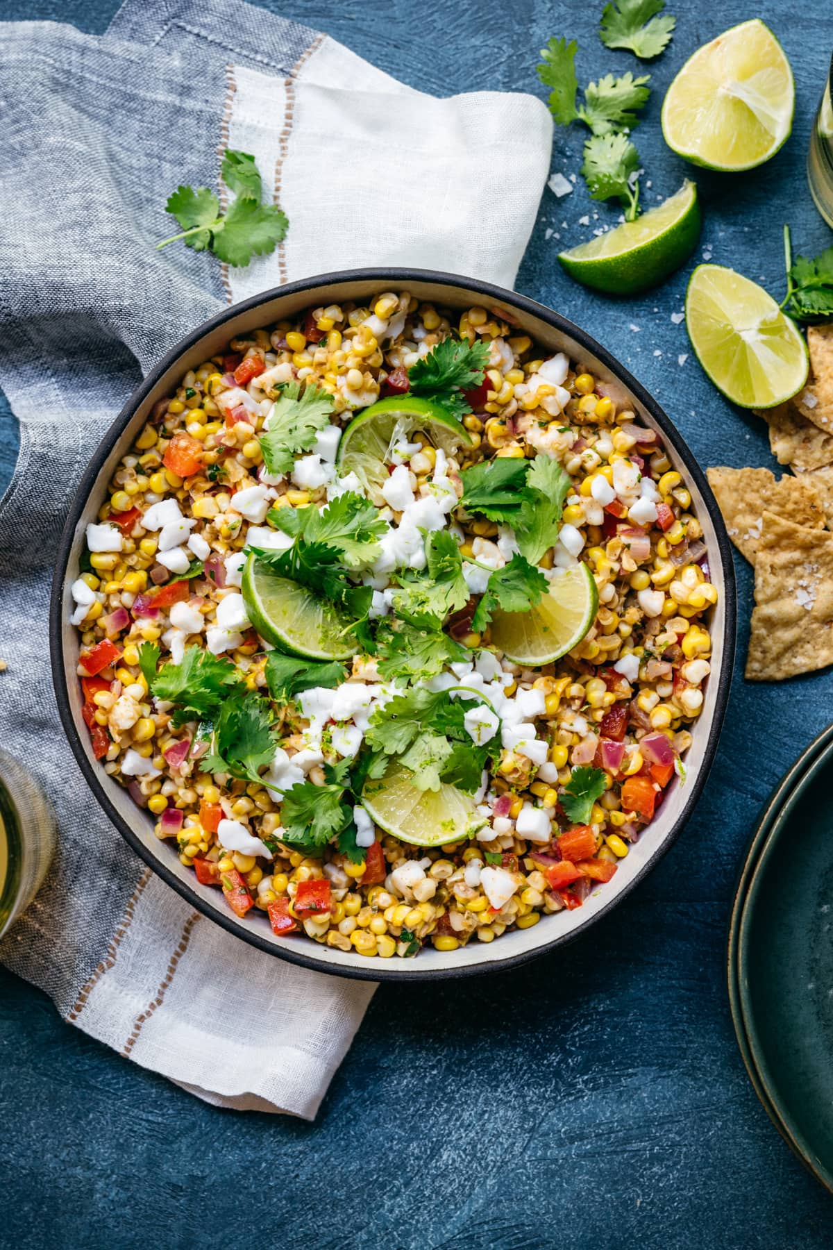 overhead view of bowl of vegan mexican street corn salad with limes and cilantro