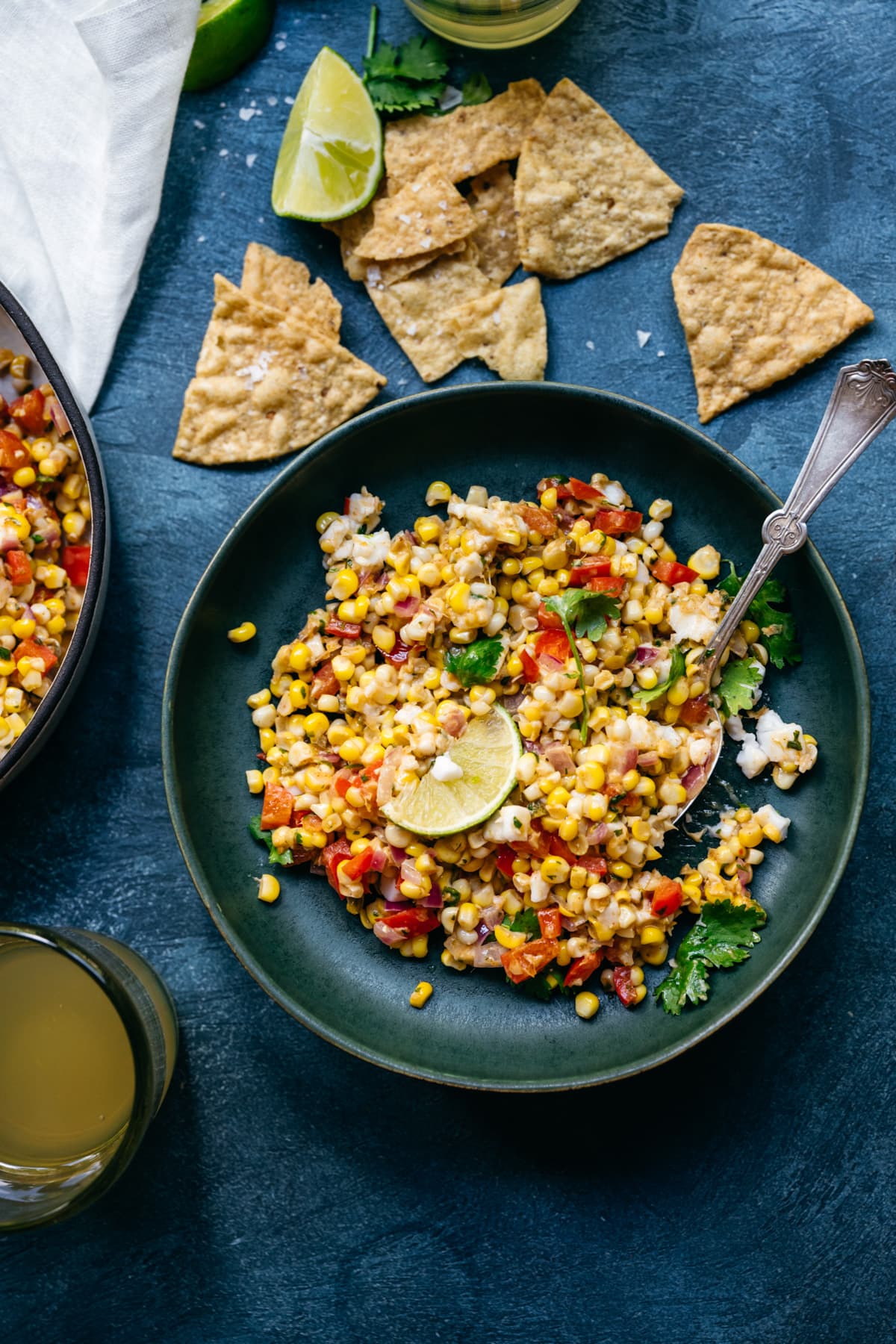 overhead view of bowl of vegan mexican street corn salad with limes and cilantro
