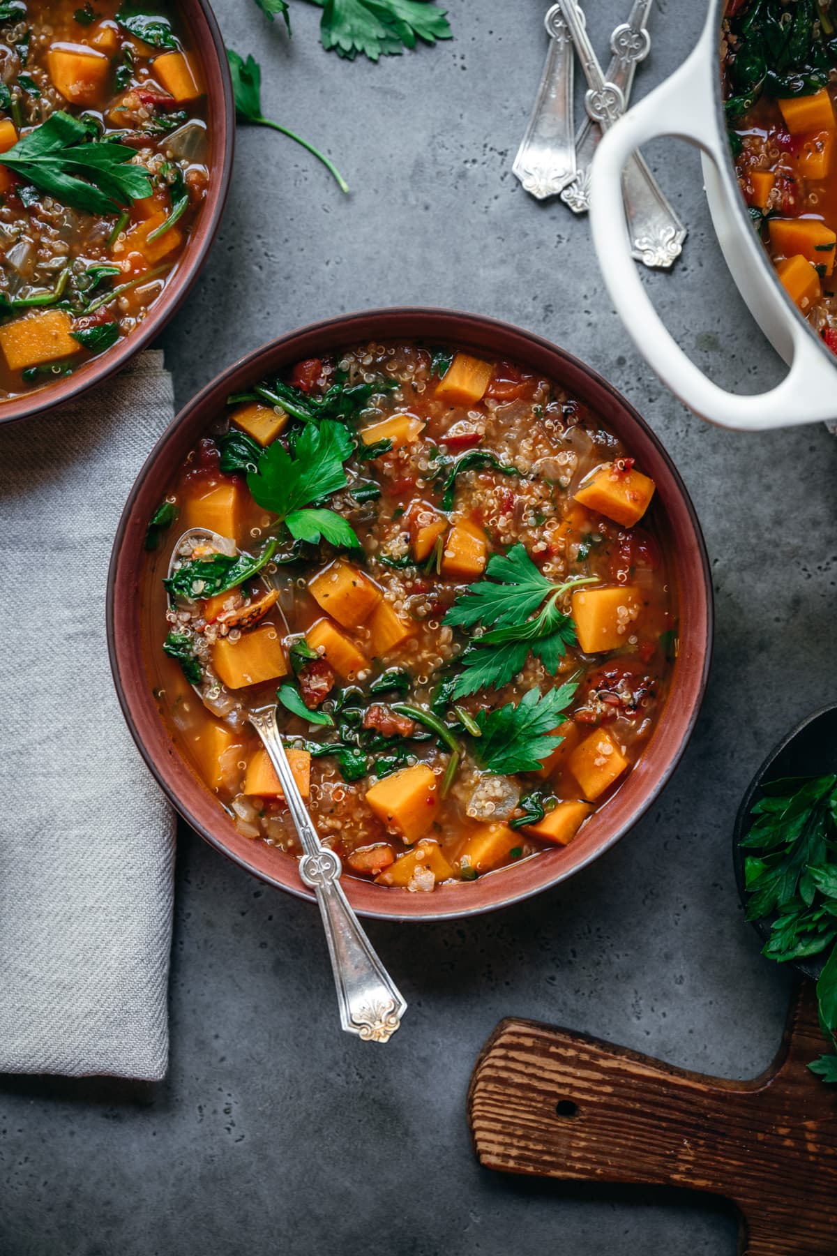 overhead view of quinoa vegetable soup with sweet potatoes in bowl with spoon.